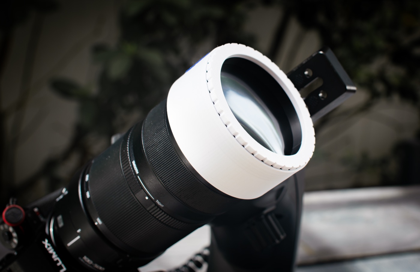 The finished filter pushed onto a telephoto lens on a tripod, seen from the front three-quarter angle.